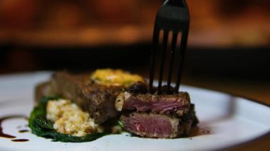 Restoranda biftek tabağı. Ispanaklı sığır filetosu, mısır, patates kızartması ve karatahta sosu var. Güneşli bir yerde çekilmiş. Yüksek kalite 4k görüntü