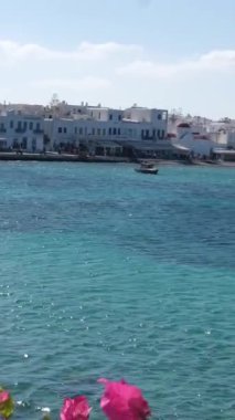 Yunanistan 'daki Mykonos Adası' nın güzel manzarası pırıl pırıl mavi deniz, demirlemiş tekne ve yatlar, parlak güneşli gökyüzü ve seyahat ve turizm için ideal büyüleyici kıyı manzarası.