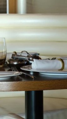 Zarif masalar, şık sofra takımları, şarap ve su bardakları ve ortasında dekoratif romantik loş bir lamba olan şık bir restoranda oturmak. Yüksek kalite 4k görüntü