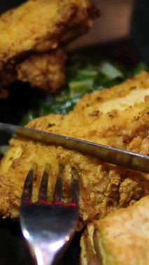 Restoranda çatal ve bıçakla yenen siyah bir tabakta kızarmış kanatlar. Yüksek kalite 4k görüntü