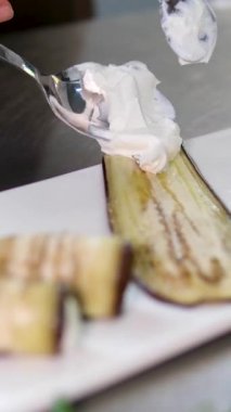 Cenin ve ricotta 'dan yapılmış yumuşak kremalı peyniri ince kabak ve patlıcan dilimlerine yayan kadın elleri sonra renkli tabaklarla çevrili iştah açıcı vejetaryen atıştırmalıkları yuvarlıyor..