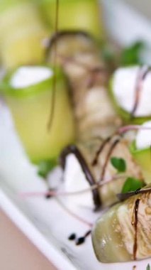 Cenin ve ricotta 'dan yapılmış yumuşak kremalı peyniri ince kabak ve patlıcan dilimlerine yayan kadın elleri sonra renkli tabaklarla çevrili iştah açıcı vejetaryen atıştırmalıkları yuvarlıyor..