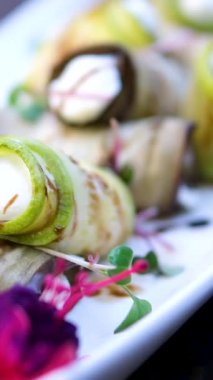 Cenin ve ricotta 'dan yapılmış yumuşak kremalı peyniri ince kabak ve patlıcan dilimlerine yayan kadın elleri sonra renkli tabaklarla çevrili iştah açıcı vejetaryen atıştırmalıkları yuvarlıyor..