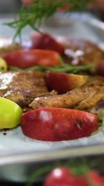 Elma ve biberiye ile ördek bacağı pişirme işlemi. Genç bir kadın yemek hazırlar, pişirir ve dekore eder. Ev yapımı kırsal mutfak atmosferini gösterir..