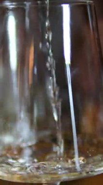 Beyaz şarabın yakın görüntüsü, karanlık restoranların şık yemek atmosferinde kadehlere dökülüyor. Lüks kutlama içeceği servis videosu..