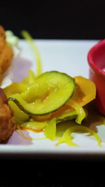 Altın hamurlu çıtır karnabahar kırmızı kâse içinde beyaz soslu dikdörtgen tabakta servis edilir..