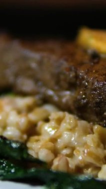 Beyaz tabak gurme yemeğinde ıspanak ve tereyağlı orta pişmiş biftek. Yemek fotoğrafçılığını kapat..