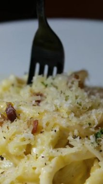 İtalyan makarnası pişirmek. Şampiyon Fetuçin ve fesleğenli krema. Şef makarna maşasıyla makarnayı karıştırır. Yakın plan, iştah açıcı yemek. Yüksek kalite 4k görüntü