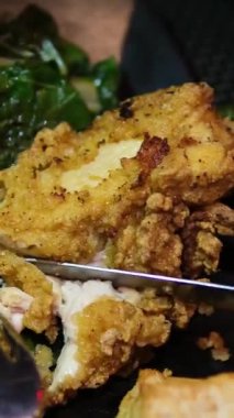 Altın fırında tavuk kanatları taze ıspanakla birlikte dikdörtgen siyah bir tabakta servis edilir. Bıçak ve çatal kesimi aksiyon vurguları dokusu, çıtır çıtır kaplama ve taze et.