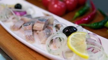 Ringa balığı parçaları yakın çekim bir tabakta yatıyor. Yağ ve baharatlı ringa filetosu. Aperatif olarak marine edilmiş balık. Deniz ürünleri. Yüksek kalite 4k görüntü