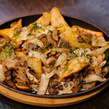 Kızarmış şampiyon mantarlı kabuklarda haşlanmış ve kızartılmış bebek patatesler ve siyah bir kızartma tavası. Yeşil arka plan, üst manzara. Yüksek kalite fotoğraf