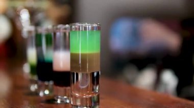 Barmen barda renkli katmanlı içkiler hazırlıyor. Yüksek kalite 4k görüntü