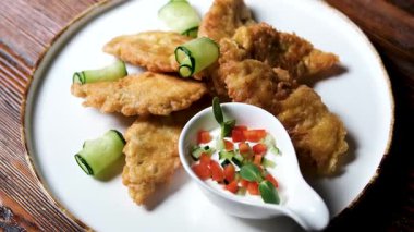 Salatalık dilimleriyle süslenmiş hırpalanmış balık, şefin eldivenleri, siyah lateks eldivenler. Yüksek kalite 4k görüntü