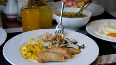 Beyaz tabakta mısır ve pirinç erişteli kızarmış Vietnam böreği, portakal ve ananas suyu ve arka planda sıcak çorba, otantik Asya yemek masası sahnesi..