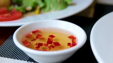 Kızarmış Vietnam usulü çıtır çıtır tavuk eti geleneksel balık sosu nuoc mama ile kırmızı biber dilimli küçük bir kasede otantik Asya sokak yemeği olarak servis ediliyor..