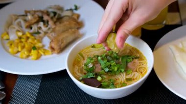 Kadınlar taze limonu geleneksel Vietnam Pho şehriye çorbasına sığır eti, pirinç eriştesi ve bitkilerle sıkıyor. Vietnam 'ın otantik aromatik çorbasından buhar yükseliyor..