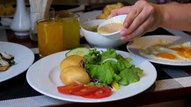 Salatalı taze salata, salatalık ve kremalı hardal tohumu soslu vişneli domatesler. Beyaz bir tabakta iki yumuşak Banh Bao buharlı çörekle servis ediliyor..