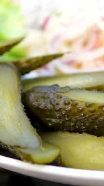 Salatalıklı salatalık turşusu ve kırmızı soğanlı lahana turşusu, lezzetli ve doğal probiyotik açısından zengin ev yapımı sağlıklı atıştırmalıkları temsil eden zarif bir restoran tarzında servis edilmiş beyaz tabak..