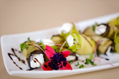 Patlıcan ruloları keçi peyniri ile doldurulmuş yeşil maydanoz ve çiçeklerle süslenmiş. Üst Manzara. Yüksek kalite fotoğraf