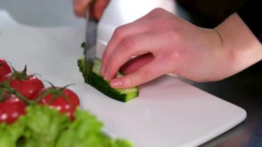 Yüzeyde salatalık doğrama, evde yemek pişirme, salata için sebze hazırlama, vejetaryen yemekleri ve ev yapımı tarifler. Yüksek kalite 4k görüntü