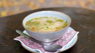 Kırsal ahşap arka planda ev yapımı sebze çorbası. Bir kase tavuk suyu çorbası. Ukrayna süsüsüyle işlenmiş peçete