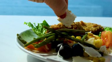 Yunan salatasının pişirme süreci. Bir kase Yunan salatasına peynir ekleyen bir kadın. Salataya peynir ekle.