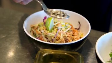 Evde salata karıştıran genç ve yakışıklı bir adam. Susam tohumları serpin.