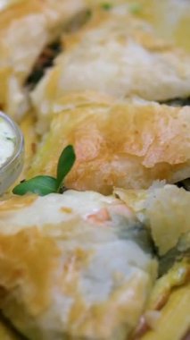 Kırmızı balık, brokoli ve yumurtalı bir turta beyaz bir tabakta sunulur. Çatal ve bıçak kullanarak, turtanın bir kısmı tatmak için kesilir. Yüksek kalite 4k görüntü