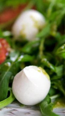 Beyaz tabakta taze Caprese salatası. Caprese, tuz ve zeytinyağıyla tatlandırılmış taze mozzarella, domates ve tatlı fesleğenden yapılmış İtalyan salatasıdır. Yiyecekler. Yüksek kalite 4k görüntü