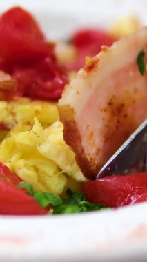 Çırpılmış yumurta, pastırma ve domates. Beyaz tabakta kahvaltı. Güneşli bir sabahta yemek. Yakın plan yumurta. Yüksek kalite 4k görüntü