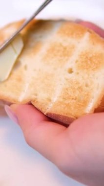 Bir parça kızarmış ekmeğe yumuşak tereyağı sürüyorum. Kahvaltı tostu yapıyorum. Yüksek kalite 4k görüntü