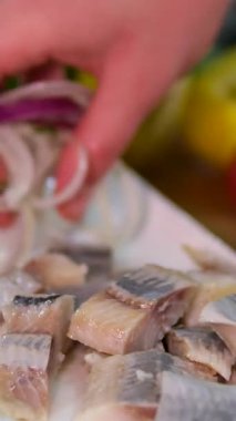 Bir aşçının kadın ellerine yakın plan yeşil soğan ve soğanlı tuzlanmış ringa balığı salatası. Yüksek kalite 4k görüntü