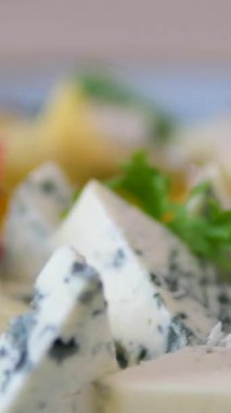 Zeytin ve taze yeşilliklerin yer aldığı Lezzetli Peynir Tabağının tadını çıkarın. Yüksek kalite 4k görüntü