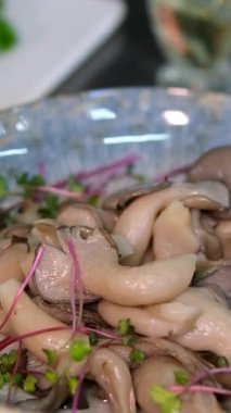 Canlı ve sağlıklı bir salatayı karıştıran ellerin yakın çekimi. Kırpılmış kırmızı ve sarı dolma biber, mantar ve ceviz berrak bir cam kasede karıştırılır. Ev yapımı yemek. Mantar salatası hazırlığı