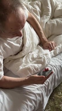 Yaşlı bir adam, telefon ve sosyal medya için gülümseme, evdeki yatakta mesajlaşma veya iletişim. Çevrimiçi konuşmada rahatlayan, gezen ya da cep telefonunda yazan mutlu son sınıf öğrencisi..