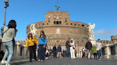Bir grup insan, Ponte Sant Angelo turistleri Castel Sant Angelo 'ya dayanan etkileyici melek heykelleri sergiliyorlar ve Vatikan şehrine doğru tarihi bir yürüyüş yolu sunuyorlar. İtalya Roma 11.27.2025