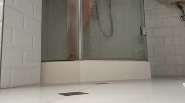Duş suyu ve banyoda çıplak bacağa dokunan bulanık kadın. Kadınlar tuvalette banyo yaparken, taze püskürtme jetleri düşüyor. Güzellik rutini. Yüksek kalite 4k görüntü