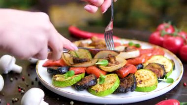 Bıçak ve çatal, tabağın yüzeyine konmuş ızgara sebze soğan biberi mantarlarını kesmek ve yemek için. Yüksek kalite 4k görüntü