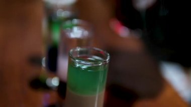 Becerikli barmen gece bir barda kokteyl hazırlıyor, sıcak ışık altında güzel kadehler oluşturmak için renkli içkiler döküyor. Yüksek kalite 4k görüntü