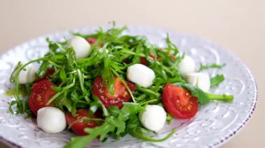 Taze Caprese salatasına zeytinyağı döküyorum. Caprese, tuz ve zeytinyağıyla tatlandırılmış taze mozzarella, domates ve tatlı fesleğenden yapılmış İtalyan salatasıdır. Yiyecekler. Yüksek