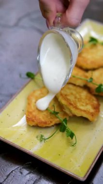 Ekşi kremalı ve siyah tabakta salatalıklı patates gözlemesi. Yüksek kalite 4k görüntü