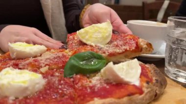 Pizza mozzarella fesleğeni, yeşil ojeli pizza elleri salam ve pastırma ile lezzetli bir pizza. Arka planda Sezar salatası ve kahve kafe yemeğini tamamlar..