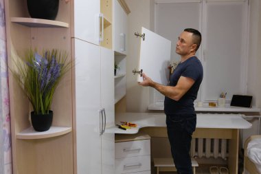 Baba, kızının odasındaki dolap kapısını tamir ediyor. Aile değerleri: iyi ebeveyn-çocuk ilişkileri. Dolap kapısını tamir etme sürecini gösteren bir video seti