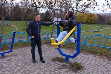 Aile değerleri, baba ve kız soğuk havada doğa gölünde yürüyor, kahve içiyor, gülüyor, oyun alanında oynuyor, çocukluk anılarını anlatıyor, yatay barlarda çalışıyor..