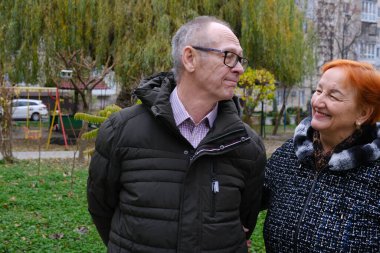 Yaşlı bir çift parkta kol kola yürüyor, doğanın tadını çıkarıyorlar. Ağaçlar çifti çevrelemiş, huzurlu, huzurlu bir park ortamı yaratmışlar. Yaşlı bir çift gün boyunca dışarıda parkın tadını çıkarıyor. Yüksek kalite 