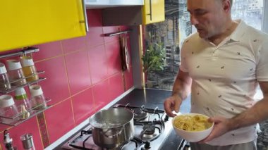 Baba ve kızı mutfakta makarna pişiriyor. Aile değerleri: Ailenle evde yemek yemek. Sarı mutfak. Modern iç mekan. Yüksek kalite fotoğraf