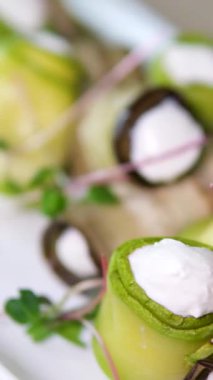 Aşçı şefi patlıcan kabaklı vejetaryen rulolarını kafede ceviz servis tabağıyla süslüyor, elleri siyah eldivenli yakın plan. Yemek servisi, restoranda yemek hazırlama. Sağlıklı organik ürünler.