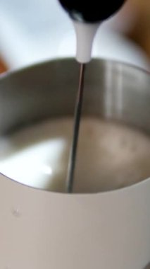 Metal bir sürahide süt buharı yapan barista köpüren bir değnekle hazırlanan buğulanmış sütün yakın çekimi. Yüksek kalite 4k görüntü