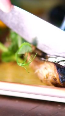 Siyah tabakta limonlu ızgara balık. Izgara uskumru. Çatal ve bıçakla kesilmiş.