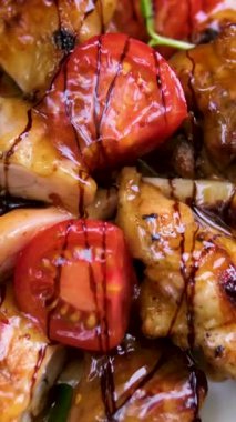 Bir kase tavuklu patlamış mısır, üzerine tatlı ve ekşi sos serpilmiş susam tohumları serpiştirilmiş. Mavi bir seramik kasede servis edilen domates, salatalık ve marulla birlikte. Yüksek kalite 4k görüntü